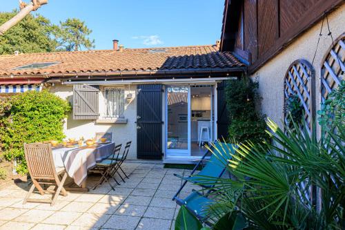 une terrasse avec une table et des chaises ainsi qu'une maison dans l'établissement Maison Kabâna - Welkeys, à Capbreton