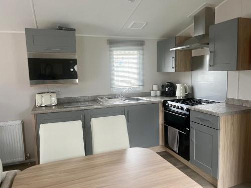 a kitchen with a sink and a stove top oven at Surfside Bliss - Cayton Bay Park caravan in Scarborough