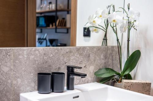 a bathroom sink with a black faucet and flowers at Alte Bildhauerei in Aurach bei Kitzbuhel