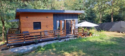 a small log cabin with a porch and an umbrella at Szalonka Vendégház Kemence in Kemence