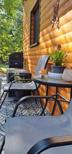 a patio with two chairs and a grill and a table at Szalonka Vendégház Kemence in Kemence