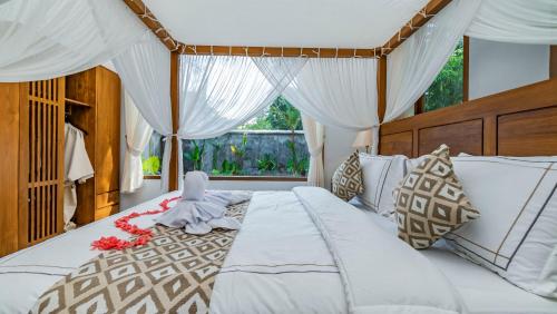 a bedroom with a large white bed with a canopy at Suweca House in Ubud