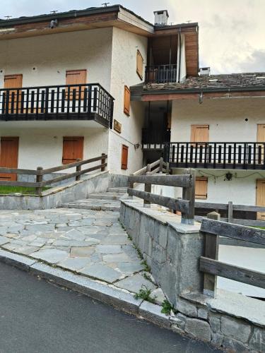 a white building with wooden doors and a balcony at Champoluc Apartment in Champoluc