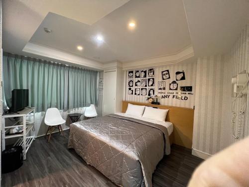 a bedroom with a bed and a table and a desk at Joy Garden Hotel in Kaohsiung