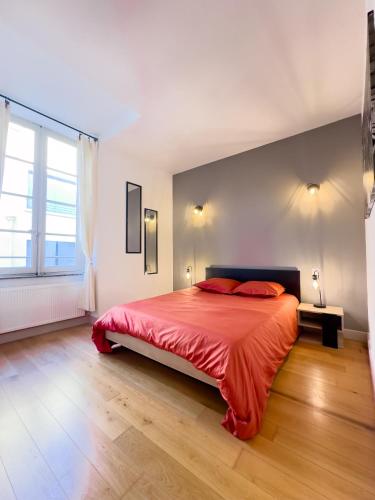 Cette chambre comprend un lit avec des draps rouges et une grande fenêtre. dans l'établissement La Cité Voltaire, à Carcassonne