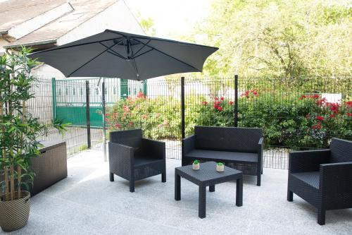 - une terrasse avec 2 chaises, un parasol et une table dans l'établissement Djial - proche de CDG et du Parc Asterix, à Dammartin-en-Goële