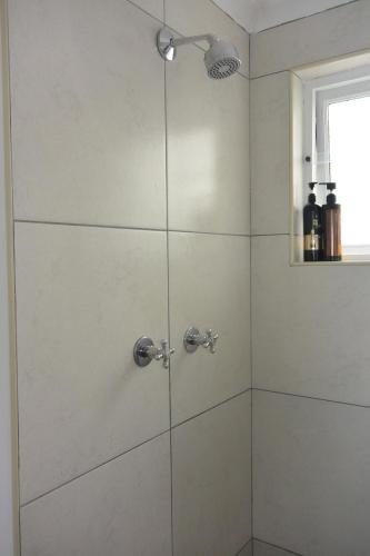 a shower with a glass door in a bathroom at Nirvana Cottage in Cape Town