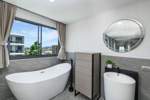 ein Badezimmer mit einer großen weißen Badewanne und einem Spiegel in der Unterkunft Brand New Luxury 3BR with Private Hammam in Chalong 
