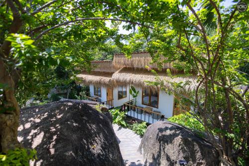 a house with a thatched roof in the woods at BOHO Boutique Bungalows in Baan Tai