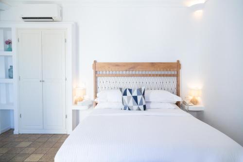 a white bedroom with a large white bed with pillows at Pantelia Suites in Fira