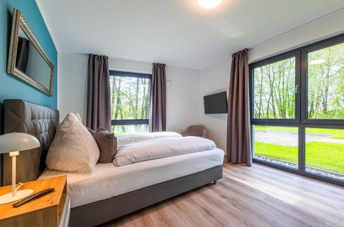 a bedroom with a bed and a large window at Yoga-Oase am Krakower See - Erdgeschoss mit Terrasse, Kamin & Sauna in Krakow am See