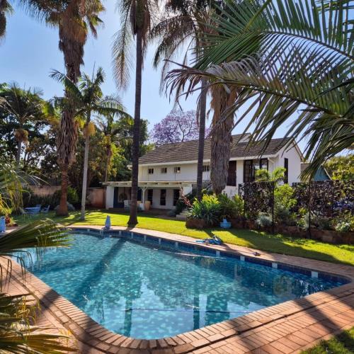Argyll Guest House في هراري: مسبح أمام منزل به أشجار نخيل