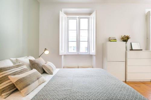 a white bedroom with a bed and a window at Duplex Fabuloso junto ao Rio, Ar Condicionado in Cruz Quebrada