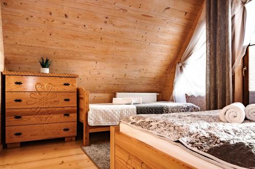 two beds in a room with wooden walls at Domki Malcykówka z własnym Jacuzzi - w cenie in Ząb