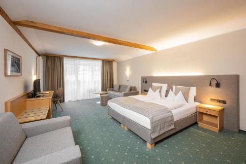 a hotel room with a bed and a couch at Wirtshaushotel Alpenrose in San Lorenzo di Sebato