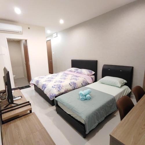 a room with two beds and a television in it at Kozi Square Kuching in Kuching