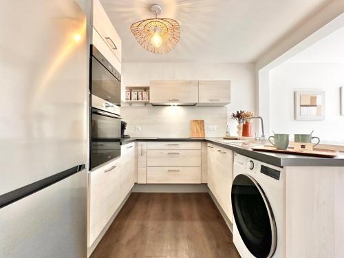 une cuisine avec des armoires blanches et une laveuse et une sécheuse dans l'établissement Le Bobochic - Calme & Élégance au Cœur de la Ville, à Mont-de-Marsan
