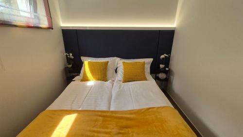 a bedroom with a bed with yellow and white pillows at Tófény Őrségi Vendégház in Zalalövő