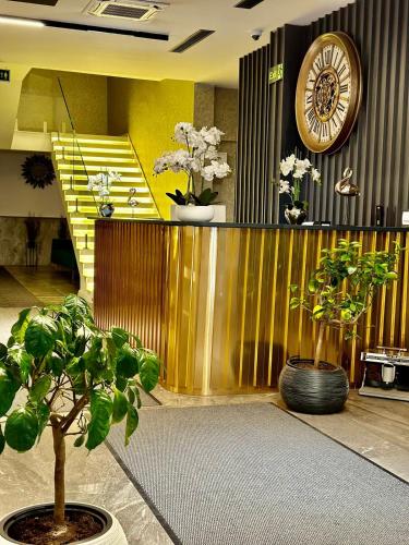 a lobby with a clock on a wall with plants at Ador Hotel North Mitrovica in Mitrovicë