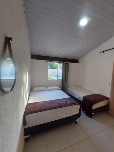 two beds in a small room with a window at Quarto em Guarapari 5 min da praia in Guarapari