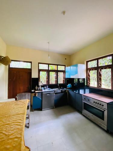 a large kitchen with blue cabinets and counters at Havindu Nethmika in Horangalla