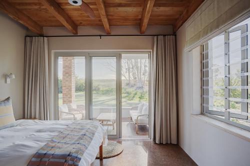 a bedroom with a bed and a large window at Bokrivier Cottages in Greyton