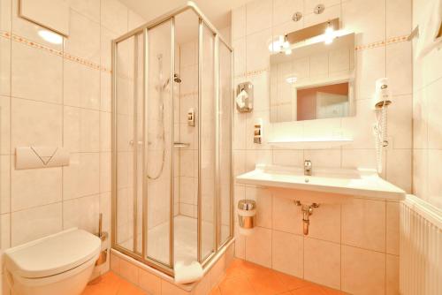 a bathroom with a shower and a toilet and a sink at Hotel Auf Wolke 8 in Trostberg an der Alz