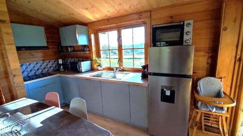 - une cuisine équipée d'un réfrigérateur et d'une table dans une cabine dans l'établissement Le chalet de la presle, à Mazerny