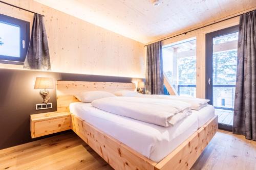 a bedroom with a large bed with white sheets at Naturchalets Turracher Höhe by ALPS RESORTS in Turracher Hohe