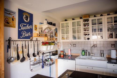a kitchen with white cabinets and utensils on the wall at Yello Homes - Gemütliche und luxuriöse Wohnung - mit Sauna, Garten, und Heimkino für 6 Personen in Anger