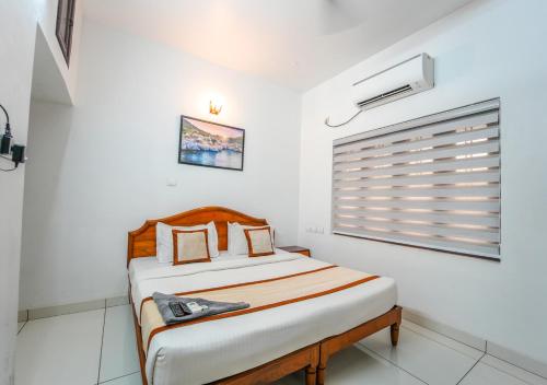 a bed in a white room with a window at Pop Tavern Kovalam Beach Villa by VOYE HOMES in Kovalam