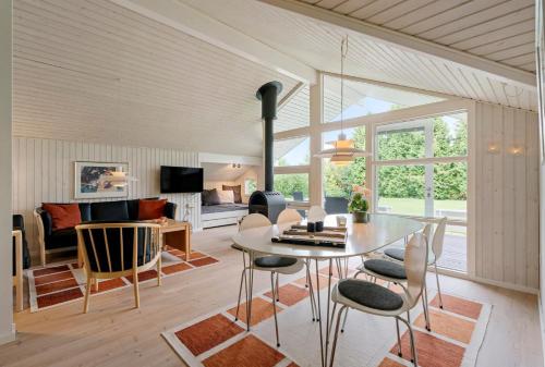 a dining room and living room with a table and chairs at Summer House Close To Nature And Beach in Dronningmølle