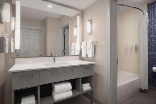 a bathroom with a sink and a tub and a mirror at Homewood Suites by Hilton Alexandria in Alexandria