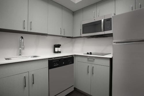 a kitchen with white cabinets and a sink and a refrigerator at Homewood Suites by Hilton Alexandria in Alexandria