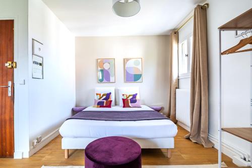 - une chambre avec un grand lit et un tabouret pourpre dans l'établissement Studio coloré proche Paris Parc des Princes- II, à Issy-les-Moulineaux