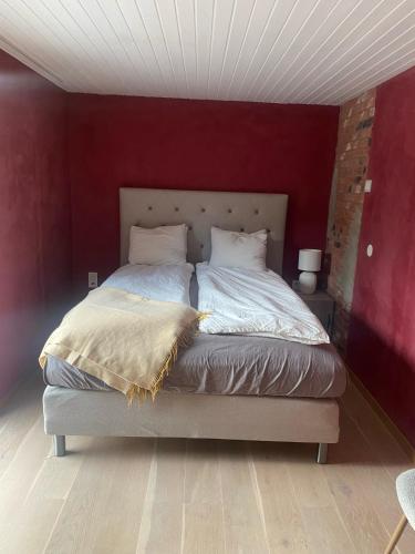 a bedroom with a large bed with a red wall at County House - Ingarö in Ingarö