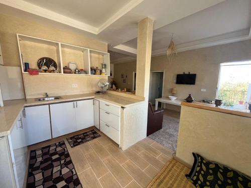 Una cocina grande con gabinetes blancos y una ventana. en Tigmi Lkdrour, en Taghazout