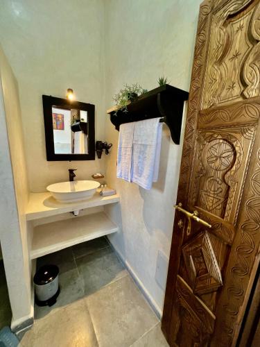 a bathroom with a sink and a wooden door at Villa Serinie in Essaouira