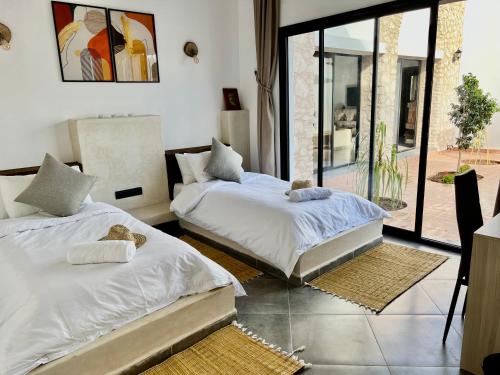 two beds sitting in a room with a window at Villa Serinie in Essaouira