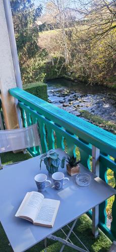 a blue bench with an open book and two cups and a book at Escapade Au Calme De La Rivière in Métabief