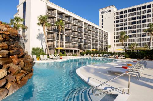 a hotel pool with chairs and a resort at Hilton Galveston Island Resort in Galveston