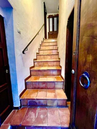 a staircase in a house with a wooden door at PienzaLettings Studio & Room in Pienza
