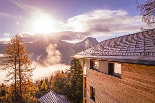 a view of a house with the sun in the background at Naturchalets Turracher Höhe by ALPS RESORTS in Turracher Hohe