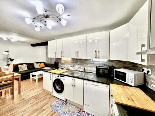 une cuisine avec des armoires blanches et un salon dans l'établissement ApartHotel Riviera - ANGLE DROITE - Old town Promenade des Anglais, à Nice