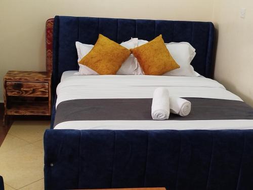 a bed with a blue headboard and two pillows at Studio in Ruaka in Nairobi
