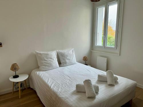 une chambre avec un lit blanc avec deux serviettes dessus dans l'établissement Chaleureux appartement entre lac et montagne, à Neuvecelle