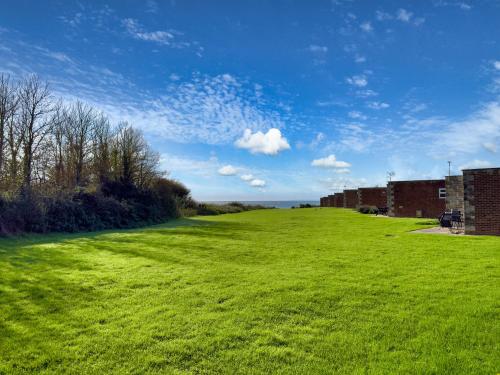 a large grassy field with buildings and a blue sky at The Retreat in Freshwater