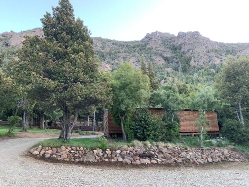 a cabin with a tree and a pile of rocks at Refugio Ventana in San Carlos de Bariloche