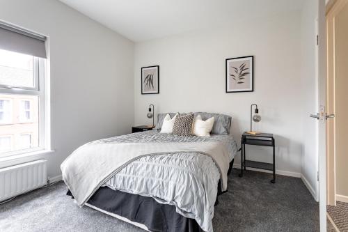 a white bedroom with a bed and a window at Belfast Holiday Home Ormeau Park in Belfast