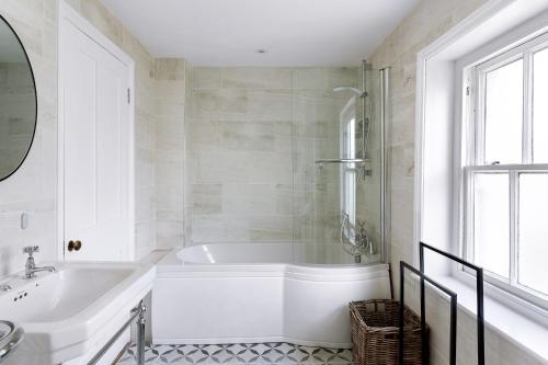 un bagno bianco con vasca e lavandino di Peaceful 3 bedroom Victorian Cottage a Honiton